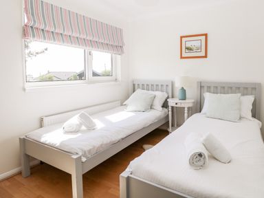 A bedroom with two single beds a window and a small table with a lamp at Seaport Lodge in Mawgan Porth
