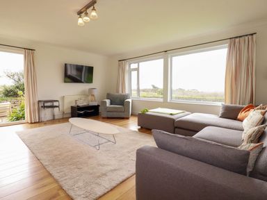 A living room with a sofa and armchair at Seaport Lodge in Mawgan Porth