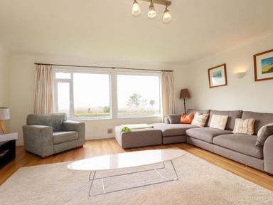 A living room with a sofa, armchair, and coffee table at Seaport Lodge in Mawgan Porth