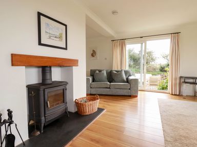 A living room with a wood stove and sofa at Seaport Lodge in Mawgan Porth