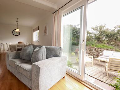 A living room with a sofa and dining area at Seaport Lodge in Mawgan Porth
