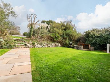 A garden with a stone pathway and grill at Seaport Lodge in Mawgan Porth