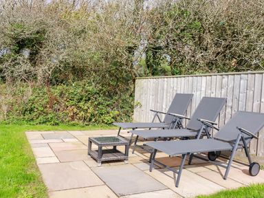A garden with deck chairs and a coffee table at Seaport Lodge in Mawgan Porth
