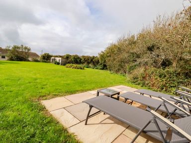 A garden with lounge chairs on a patio at Seaport Lodge in Mawgan Porth