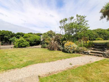 A garden with a pathway and various plants at Seaport Lodge in Mawgan Porth