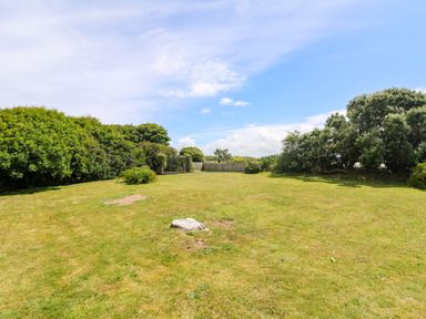 A garden with grass and bushes at Seaport Lodge Mawgan Porth