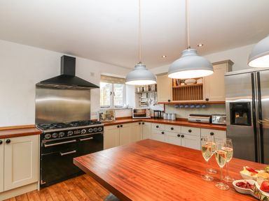A kitchen with wooden countertops and white cabinets at Lost Barn in Watergate Bay