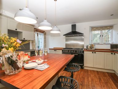 A kitchen with a wooden island countertop and modern cabinets at Lost Barn in Watergate Bay
