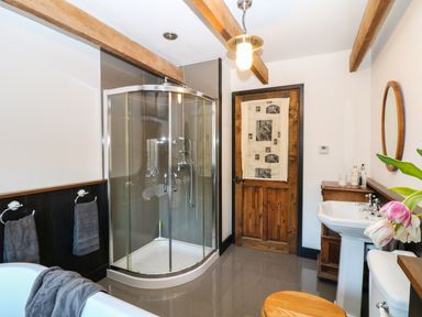 A bathroom with a corner shower enclosure a bathtub a wooden door and a sink at Lost Barn in Watergate Bay