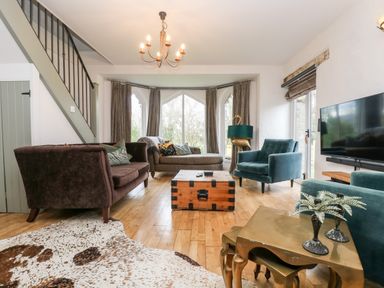 A living room with sofas a wooden chest coffee table a cowhide rug and a television at Lost Barn in Watergate Bay