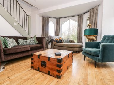 A living room with a brown sofa a gray chaise lounge a green armchair and a wooden chest used as a coffee table at Lost Barn in Watergate Bay