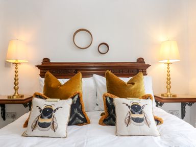 A bed with decorative pillows and lamps on bedside tables at Lost Barn in Watergate Bay