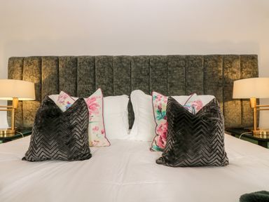 A bed with floral and dark chevron patterned pillows and two bedside lamps at Lost Barn in Watergate Bay