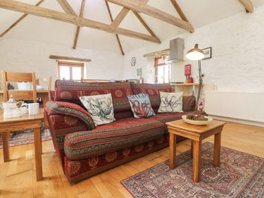 A living room with a patterned sofa and wooden coffee table with pine cones at Courtyard Nancegollan nr Porthleven