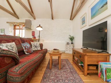 A living room with a patterned sofa table lamp television and wooden beams at Courtyard in Nancegollan nr Porthleven