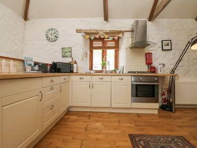 A kitchen with cream cabinets wooden floor and a window over the sink at Courtyard in Nancegollan nr Porthleven