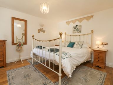 A bedroom with a metal bed frame and wooden furniture at Courtyard in Nancegollan nr Porthleven
