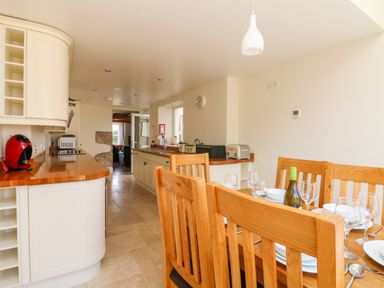 A kitchen with wooden dining table and chairs and cream cabinets at Boslow in St Just