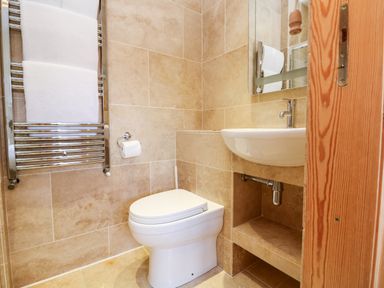 A bathroom with a toilet a sink a mirror and a towel rack at Boslow in St Just