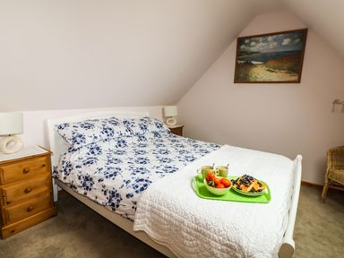 A bedroom with a bed with floral bedding and a tray with food on it at Higher Kernick Stable in Helland near Blisland