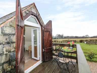 A balcony with a small round table and two chairs overlooking fields at Higher Kernick Stable Helland near Blisland