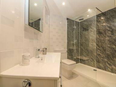 A bathroom with a sink counter and mirror a toilet and a walk in shower with dark tiled walls at Higher Kernick Stable in Helland near Blisland