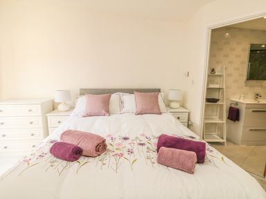 A bedroom with a bed topped with towels and pillows beside bedside tables and a lamp at Higher Kernick Stable Helland near Blisland