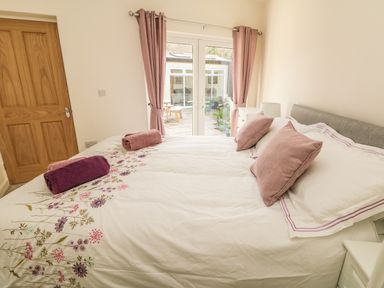 A bedroom with a double bed towels on the bed and pink curtains at Higher Kernick Stable in Helland near Blisland