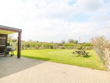 A backyard with a paved patio area a picnic table and a barbecue grill at Higher Kernick Stable Helland near Blisland