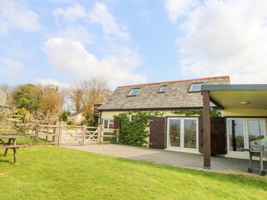 A building with skylights and wooden shutters on patio with grass and a wooden fence at Higher Kernick Stable Helland near Blisland