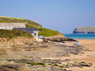 A rocky coastline with buildings near the shore and small boats on the sand at The Old Dairy in Padstow