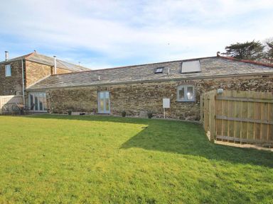 A stone building with a slate roof and green lawn in front at The Old Dairy in Padstow