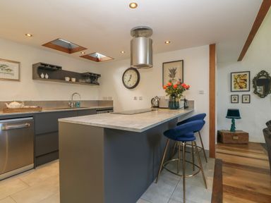 A kitchen with a central island and two blue bar stools at Hideaway in Watergate Bay