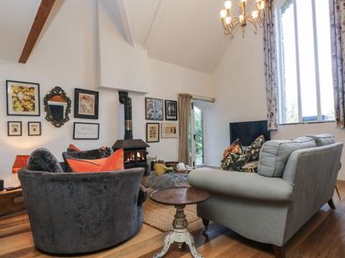 A sitting room with sofas a wood burning stove and framed pictures on the wall at Hideaway in Watergate Bay