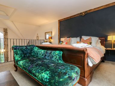 A bedroom with a wooden bed and a green upholstered bench at Hideaway in Watergate Bay