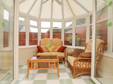 A conservatory with wicker furniture and a glass coffee table at Fairways in Woolacombe