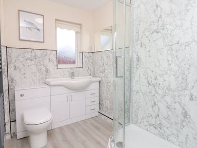 A bathroom with a toilet sink cabinet window and shower at Fairways in Woolacombe