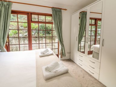 A bedroom with a bed topped with folded towels next to a wardrobe with mirrored doors at Mengarth in Cadgwith