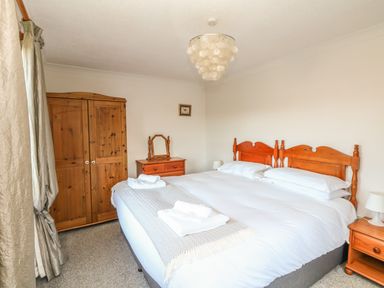 A bedroom with a double bed two wooden headboards wooden wardrobe and bedside tables with lamps at Mengarth in Cadgwith