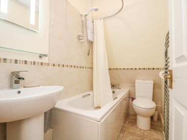 A bathroom with a bathtub shower combination toilet and sink at Gannet Watch in Coverack