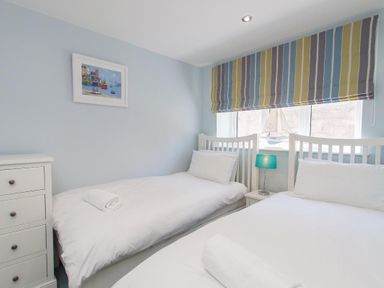 A bedroom with two single beds a striped window blind and a chest of drawers at Bayview in Brixham