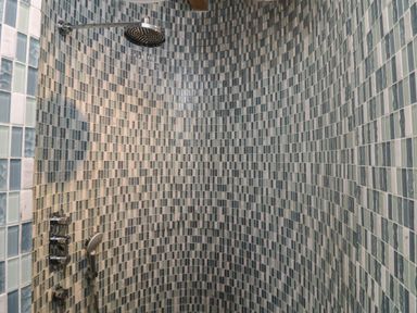 A shower area with curved mosaic tiled walls and two shower heads at Hay Loft Bolenowe Nr Portreath