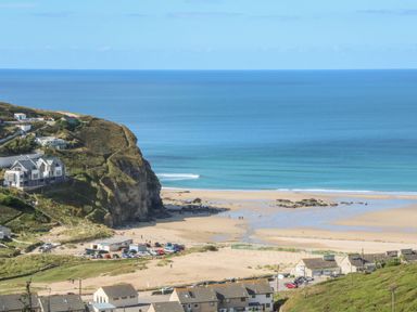 A coastal scene with cliffs houses parked cars and a sandy beach at Hay Loft in Bolenowe Nr Portreath