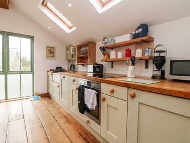 A kitchen with wooden floor cabinets shelves and appliances at Hay Loft Bolenowe Nr Portreath