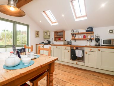 A kitchen with wooden floor and table set near large window and skylights at Hay Loft Bolenowe Nr Portreath