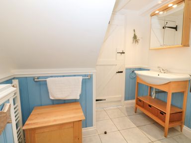 A bathroom with a wooden vanity and a white sink a white door and blue panelled walls at Trehan in St Ives