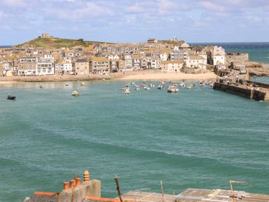 A coastal town with buildings along the shore and boats in the water at Trehan in St Ives