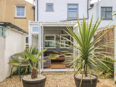 A small garden with potted plants and open glass doors leading to a living room at Trevean in Portreath