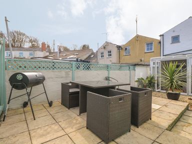 An outdoor patio with a barbecue grill and a dining table with four chairs near a house at Trevean in Portreath