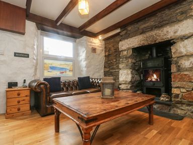 A living room with a leather sofa wooden coffee table stone fireplace and side cabinet at Trevean in Portreath